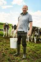 I take good care of my cattle. Full length portrait of a male farmer standing with a bucket of feed on his dairy farm.