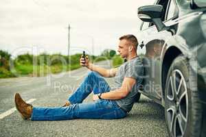 Waiting for his wheels to be towed away. a young man waiting for roadside assistance after breaking down.