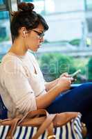 Music is a great travel companion. an attractive young woman using her smartphone while sitting on a bus.