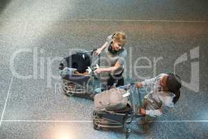 I cant wait to get on the plane. High angle shot of two attractive young women walking through an airport.
