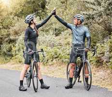 Motivation, cyclist and high five on bike break outdoors in the street. Success, goal and countryside sports environment for training. Nature, cycling and biking people exercising on scenic route.