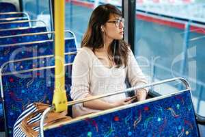 Traveling through a brand new city. High angle shot of an attractive young woman listening to music while sitting on a bus.