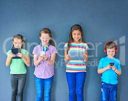 More mobile than ever. Studio shot of a group of kids using wireless technology against a blue background.