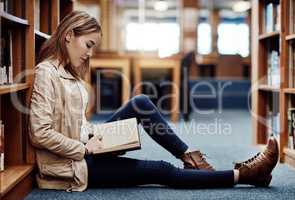 Think Ill study right here. a university student reading a book in the library at campus.