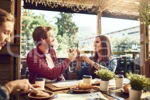 Cheers to good food and good looking people. an affectionate young couple toasting with sandwiches while enjoying themselves at lunch.