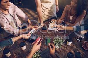 Need a smarter way to split that bill. High angle shot of a group of friends offering their bank cards to pay the bill at a cafe.