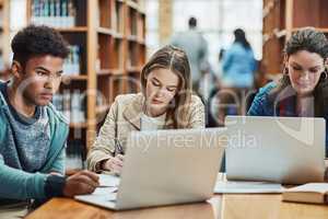 The hard work will all be worth the results. a group of university students working in the library at campus.