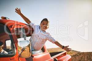 Take on life with open arms. a young cheerful boy leaning out of a red pickup truck with his arms stretched out while looking into the camera.