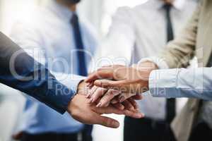 We can do this. an unrecognizable group of businesspeople standing in the office together with their hands stacked.