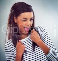 Wink if youre all about being happy. a young woman posing against a grey background.