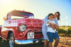 Mom and son spending some time together. a cheerful mother holding her young son and spending quality time together while standing next to a red pickup truck outside.