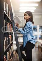 Ive always wanted to read this book. a university student using a ladder to reach a book in the library at campus.