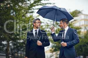 Heading off to their next meeting. two corporate businessmen travelling through the city on a rainy day.