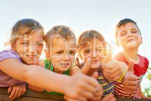 Playtime is the best time. Portrait of a group of little children showing thumbs up while playing together outdoors.