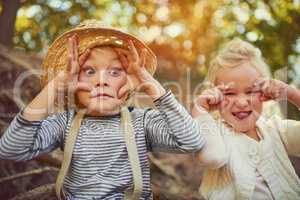 Showing off their funny character. Portrait of two little children playing together outdoors.