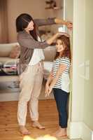 You getting so tall. a beautiful mother measuring her adorable daughters height at home.