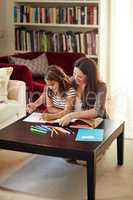 Getting help with my tasks. a beautiful mother helping her adorable daughter with her homework at home.