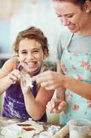 Making cookie shapes with Mommy. a mother and daughter preparing food in the kitchen at home.