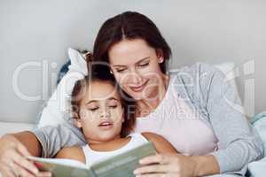 Spending her time being a perfect mother. a mother and daughter reading a bedtime story together.