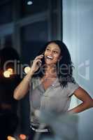Nothing like laughter to get you through the late shift. a young businesswoman talking on a mobile phone during a late night at work.