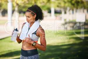 Staying hydrated after working up a sweat. a sporty young woman drinking water while exercising outside.