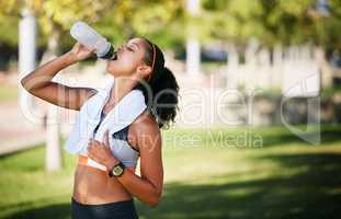 Its essential to stay hydrated. a sporty young woman drinking water while exercising outside.