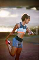 Its almost time to get started. an attractive young woman stretching before a run through the city.