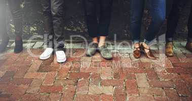 We all have our favorite pair of shoes. a diverse group of people standing together on a paved sidewalk.
