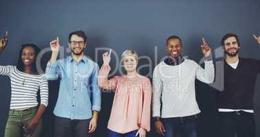 Look up and youll see why were smiling. Studio shot of a diverse group of people pointing upwards against a gray background.