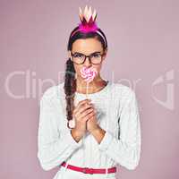 Forget the sweet talk. a young woman posing with a party crown and a lollipop against a pink background.