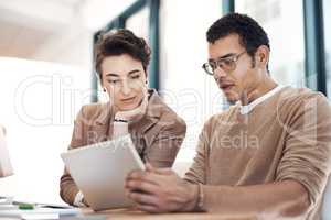 Innovation flourishes when they put their heads together. two businesspeople working together on a digital tablet in an office.