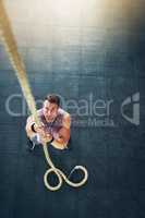 Climb like a champion. a muscular young man climbing a rope at the gym.