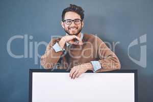 I totally back your brand. Studio portrait of a young man holding a blank sign against a grey background.