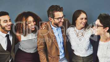 Stand together and watch each other grow. Studio shot of a group of businesspeople standing together against a gray background.