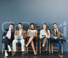 The kind of confidence you want in great candidates. Studio portrait of a group of businesspeople using wireless technology while waiting in line against a gray background.