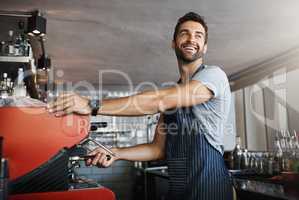 One cappuccino coming right up. a young man operating the coffee machine at a cafe.