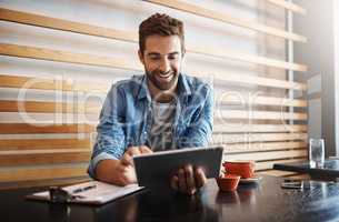 Managing his cafe the smart app way. a handsome young man using a digital tablet in a coffee shop.