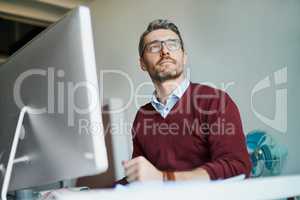 Looks like another bright and successful day. a mature businessman working on a computer in an office.