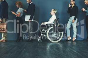 The job is open to all applicants. a woman in a wheelchair waiting in line to be interviewed.