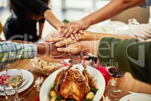 Its the time everyone gets to enjoy their families. a group of people stacking their hands at a dining table.