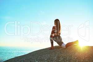 There are so many beautiful reasons to be happy. Rearview shot of a young woman practicing yoga on the beach.