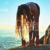 Allow yourself to let go. an athletic young woman practicing yoga on the beach.