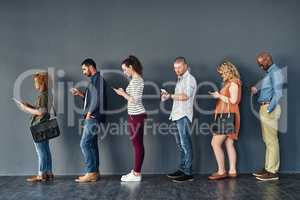 Connected in their own ways. Studio shot of people waiting in line against a grey background.