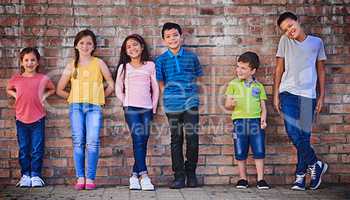 Start the bond young and watch it prosper. a diverse group of children standing against a wall outside.