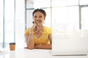 Its not work, its my passion. Portrait of a confident young businesswoman working at her desk in a modern office.