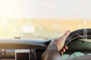 The world is in front of us. a unrecognizable man driving in a vehicle with his cellphone attached to the dashboard.