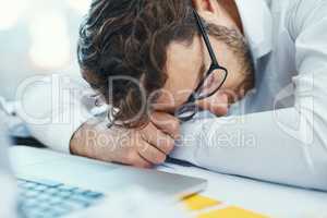 Feeling down in the dumps after a stressful work day. a young businessman with his head down on an office desk.