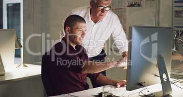 Making the most of his wisdom. two businessmen working together on a computer in their office.