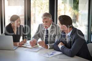 Hes the one they come to for advice. a team of businesspeople meeting at a table in the boardroom.