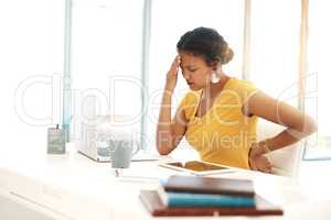 Maybe a new chair will ease this back ache. a young businesswoman experiencing stress at her desk in a modern office.